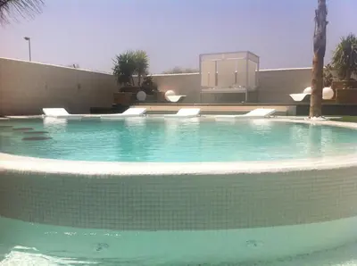 a swimming pool with blue water in front of a building at Villa Campito in El Puerto de Santa María