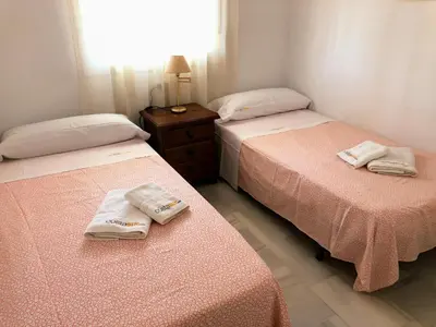 two beds in a room with towels on them at Apartamento Zinna in Chiclana de la Frontera
