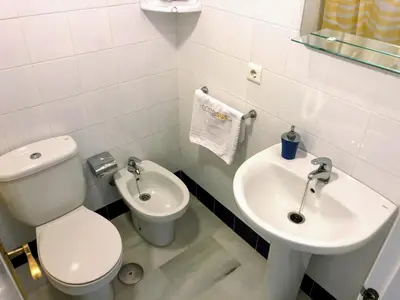 a white bathroom with a toilet and a sink at Apartamento Zinna in Chiclana de la Frontera