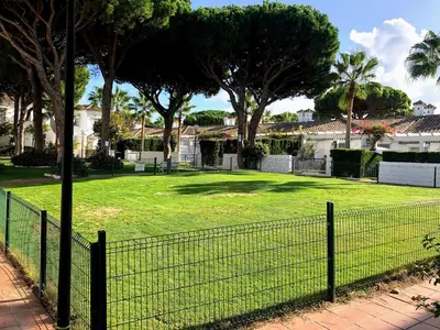 a fence in a yard with trees and houses at Apartamento Zinna in Chiclana de la Frontera
