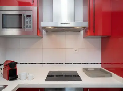a kitchen with red cabinets and a white counter top at SibsSanlucar Piletas 1ª Linea Playa Piscina Terraza Padel Parking Wifi in Sanlúcar de Barrameda
