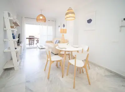 a dining room and living room with a table and chairs at SibsSanlucar Piletas 1ª Linea Playa Piscina Terraza Padel Parking Wifi in Sanlúcar de Barrameda
