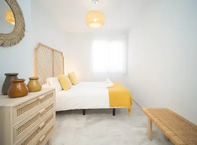 a white bedroom with a bed and a window at SibsSanlucar Piletas 1ª Linea Playa Piscina Terraza Padel Parking Wifi in Sanlúcar de Barrameda