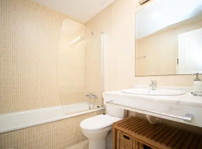 a bathroom with a sink and a toilet and a mirror at SibsSanlucar Piletas 1ª Linea Playa Piscina Terraza Padel Parking Wifi in Sanlúcar de Barrameda