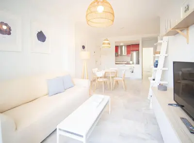 a living room with a white couch and a table at SibsSanlucar Piletas 1ª Linea Playa Piscina Terraza Padel Parking Wifi in Sanlúcar de Barrameda