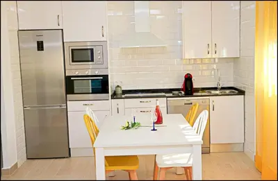 a kitchen with a white table and a refrigerator at Casa Colorado con piscina in Conil de la Frontera