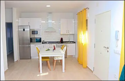 a kitchen with a white table and yellow chairs at Casa Colorado con piscina in Conil de la Frontera