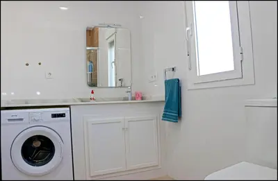 a white bathroom with a washing machine and a mirror at Casa Colorado con piscina in Conil de la Frontera