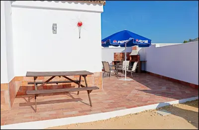 a patio with a picnic table and a blue umbrella at Casa Colorado con piscina in Conil de la Frontera