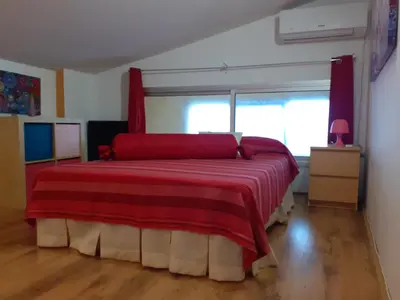 a bedroom with a large bed with a red blanket at Loft céntrico y confortable in Jerez de la Frontera