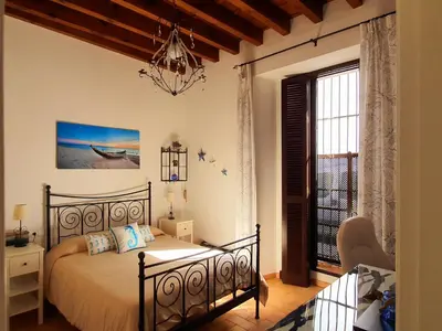 a bedroom with a bed and a window at Palacio Godoy in Sanlúcar de Barrameda