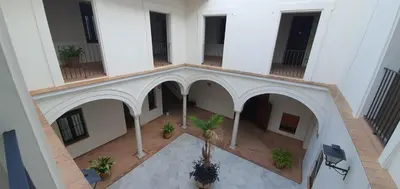a living room with a couch and a table and a window at Palacio Godoy in Sanlúcar de Barrameda