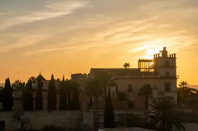 a building with a sunset in the background at JEREZ CENTRO 5 DORMITORIOS TERRAZAS CON VISTAS ALCAZAR Y PLAZA ARENAL in Jerez de la Frontera
