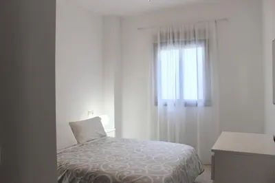 a white bedroom with a bed and a window at City CENTER and Free PARKING apartment in Jerez de la Frontera