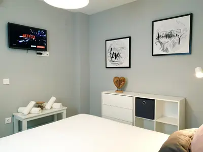 a bedroom with a bed and a tv on the wall at Sherryflat Palacio - Parking in Jerez de la Frontera