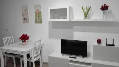 a white dining room with a table and a television at Apartamento Centro Sol Plazuela in Jerez de la Frontera