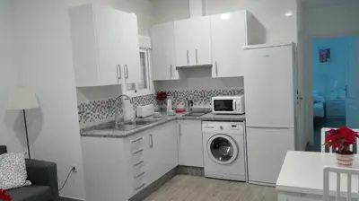 a kitchen with white cabinets and a washer and dryer at Apartamento Centro Sol Plazuela in Jerez de la Frontera