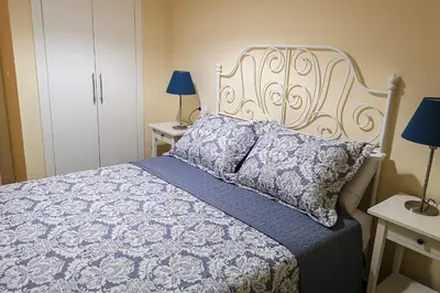 a bedroom with a bed with a blue and white comforter at Apartamentos Jerez Plaza in Jerez de la Frontera