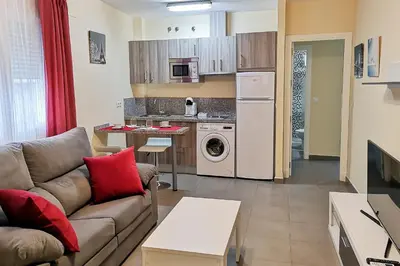 a living room with a couch and a kitchen at Apartamentos Jerez Plaza in Jerez de la Frontera