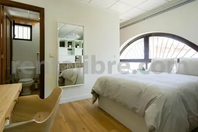 a bedroom with a bed and a desk and a bathroom at Loft24Sanlúcar in Sanlúcar de Barrameda