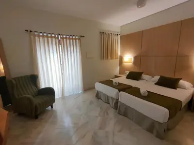 a hotel room with two beds and a chair at Hotel Boutique Convento Cádiz in Cádiz