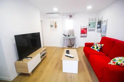 a living room with a red couch and a flat screen tv at SH L'Azotea D'Horozco. Ático con terraza. AC, WiFi in Cádiz