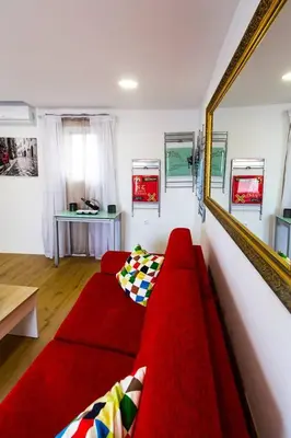 a living room with a red couch and a mirror at SH L'Azotea D'Horozco. Ático con terraza. AC, WiFi in Cádiz
