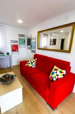 a red couch in a living room with a mirror at SH L'Azotea D'Horozco. Ático con terraza. AC, WiFi in Cádiz