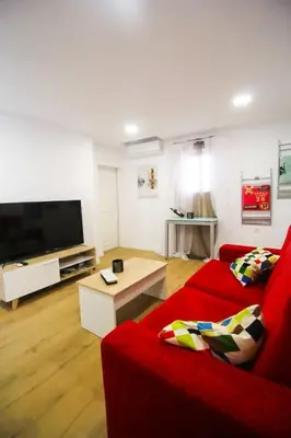 a living room with a red couch and a flat screen tv at SH L'Azotea D'Horozco. Ático con terraza. AC, WiFi in Cádiz
