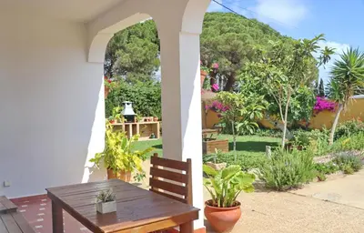 a porch with a wooden table and a garden at Chalet Pilahito in Conil de la Frontera