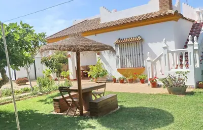 a picnic table with an umbrella in front of a house at Chalet Pilahito in Conil de la Frontera