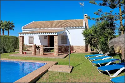 a group of lounge chairs next to a swimming pool at Casa Roche Viejo in Conil de la Frontera