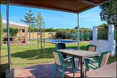 a patio with a table and chairs and a pool at Casa Roche Viejo in Conil de la Frontera