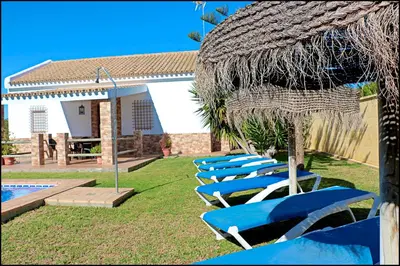 a row of blue lounge chairs next to a pool at Casa Roche Viejo in Conil de la Frontera
