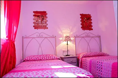 two beds in a bedroom with pink and red curtains at Casa Roche Viejo in Conil de la Frontera