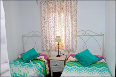 a bedroom with two beds and a table with a lamp at Casa Roche Viejo in Conil de la Frontera