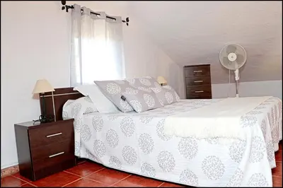 a bedroom with a bed with a white comforter and a window at Casa Roche Viejo in Conil de la Frontera