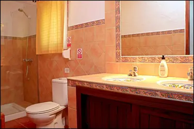 a bathroom with a sink and a toilet and a mirror at Casa Roche Viejo in Conil de la Frontera