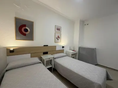 a bedroom with two beds and a desk at Hostal Bahía in Cádiz