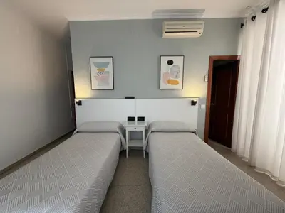 a room with two beds and a table in it at Hostal Bahía in Cádiz