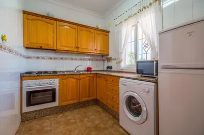 a kitchen with wooden cabinets and a washer and dryer at Chalet Pedro III in Conil de la Frontera