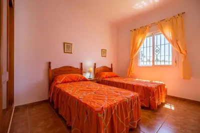two beds in a room with orange sheets at Chalet Pedro III in Conil de la Frontera