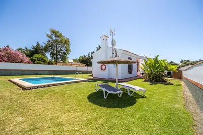 a yard with a pool and a chair and an umbrella at Chalet Pedro III in Conil de la Frontera