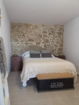 a bedroom with a large bed with a stone wall at TRIPERIA 25 in Medina Sidonia