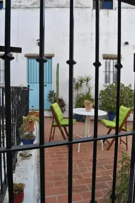 a view of a patio through a fence with chairs and a table at Casa-Palacio La Casa Empeño en Centro Histórico in Arcos de la Frontera
