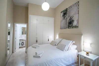 a bedroom with a white bed and a painting on the wall at Apartamento Relax in Cadiz in Cádiz