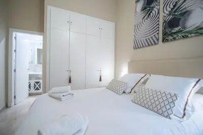 a white bedroom with a large white bed with two pillows at Apartamento Relax in Cadiz in Cádiz