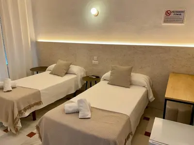 a white bedroom with two beds with blue sheets at BOHEMIA SANLUCAR in Sanlúcar de Barrameda