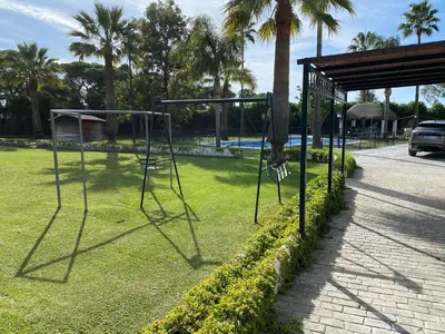 a swing set in a park with palm trees at ABULAGAR in Rota