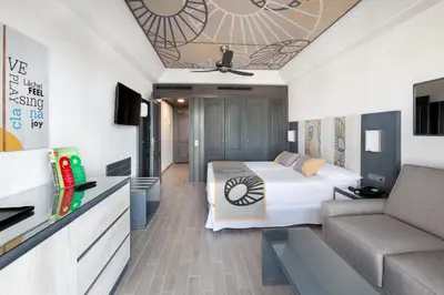 a hotel room with a bed and a couch at Hotel Riu Chiclana - All Inclusive in Chiclana de la Frontera